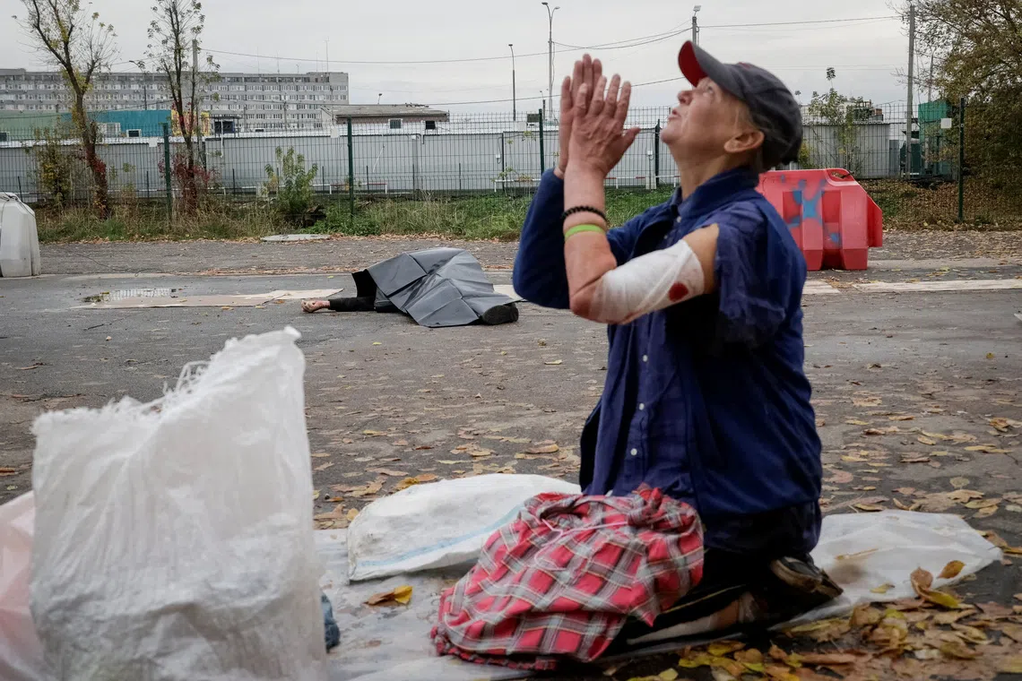 SENSITIVE MATERIAL. THIS IMAGE MAY OFFEND OR DISTURB A wounded street vendor reacts as the body of another street vendor lies on the ground next to goods at the site of a flea market hit during a Russian military strike, amid Russia's attack on Ukraine, in Kharkiv, Ukraine October 16, 2026. REUTERS/Sofiia Gatilova