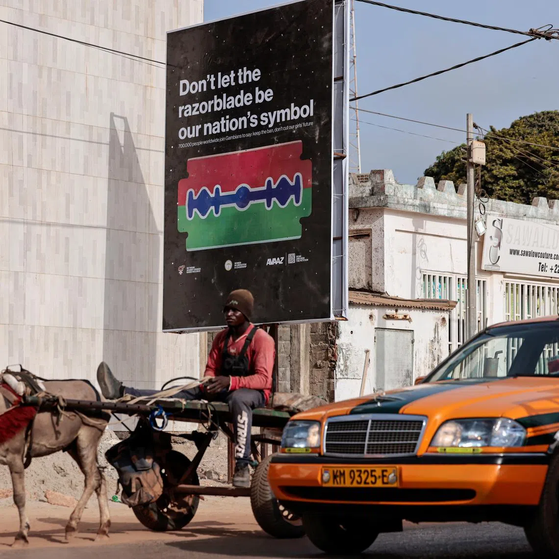 A man rides a cart past a poster advocating for an end to female genital mutilation (FGM), in Banjul, Gambia, June 6, 2024. REUTERS/Zohra Bensemra