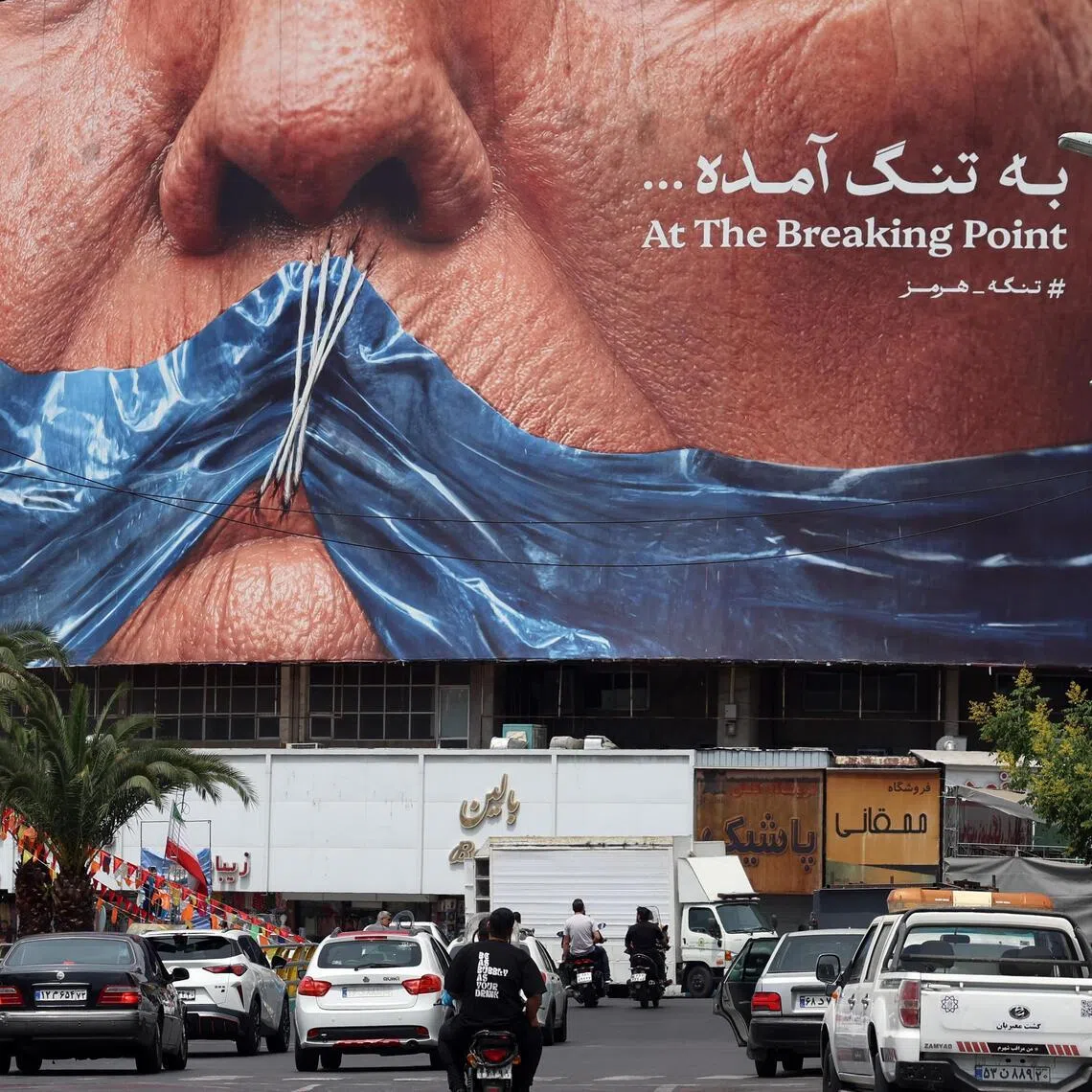 Iranians driving past a large anti-US billboard in Tehran on May 28, featuring US President Donald Trump and the Strait of Hormuz.