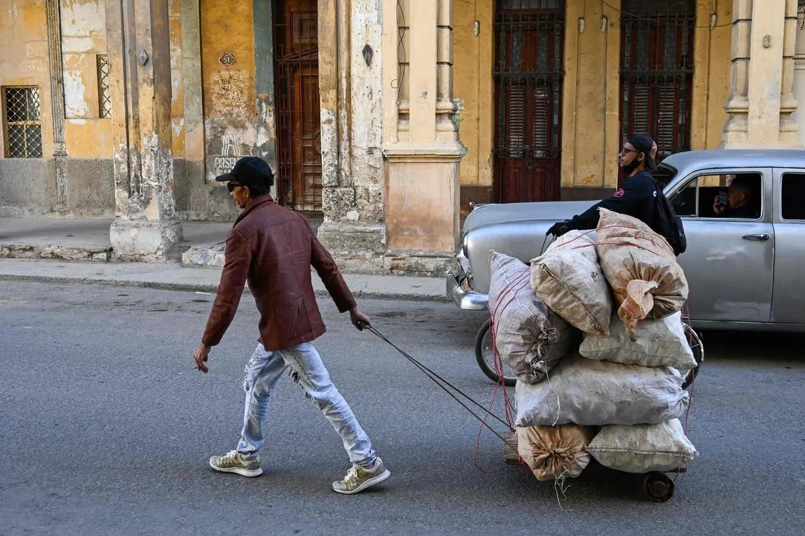A man transports raw materials in a self-made wheelbarrow along a street in Havana, Cuba, on Feb 25.