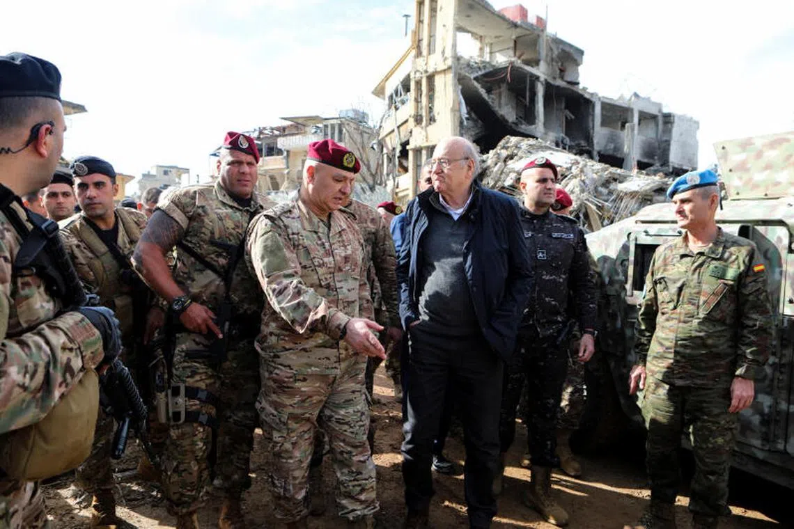 Lebanon’s caretaker Prime Minister Najib Mikati, Lebanon’s Army chief General Joseph Aoun and the Head of Mission and Force Commander of the United Nations Interim Force in Lebanon (UNIFIL) Aroldo Lazaro Saenz stand near rubble of damaged buildings from Israeli strikes, after the ceasefire between Israel and Hezbollah, during a visit to the Lebanese village of Khiam, December 23, 2024. REUTERS/Karamallah Daher