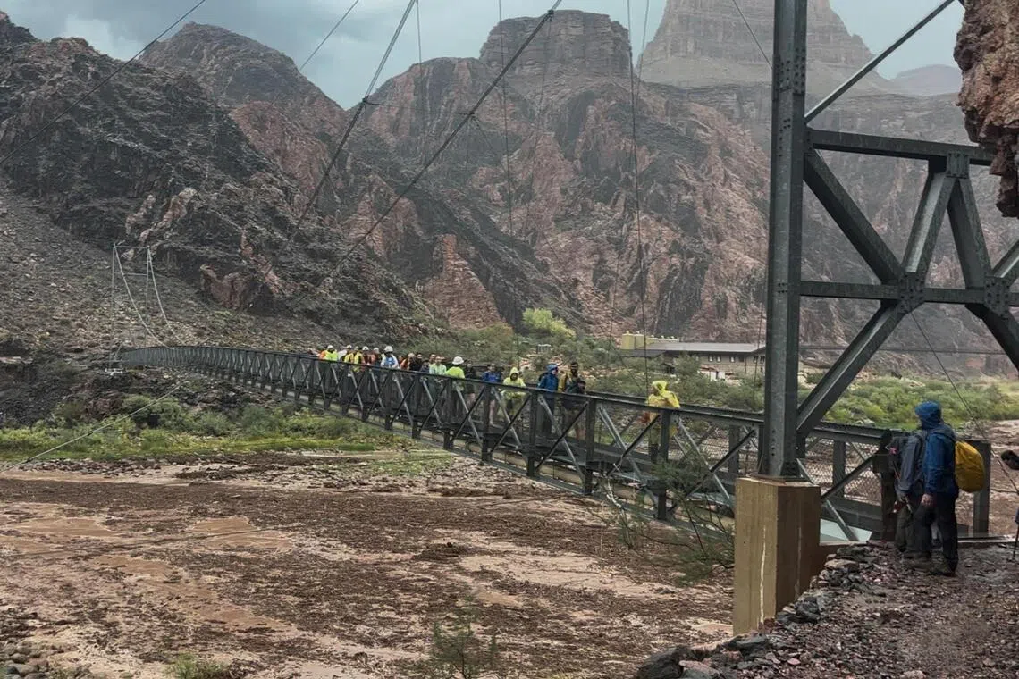A still image from video shows people crossing a bridge amid flash flooding in the Grand Canyon National Park, Arizona, on Aug 29.