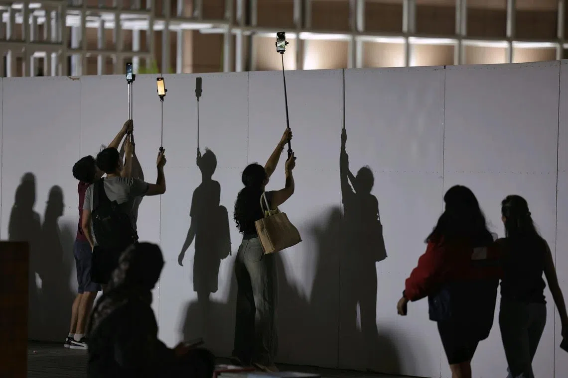 Fans trying to catch a glimpse of the Singapore Airlines Singapore Grand Prix from the link bridge between Millenia Walk and Marina Square on Sept 22, 2024. 