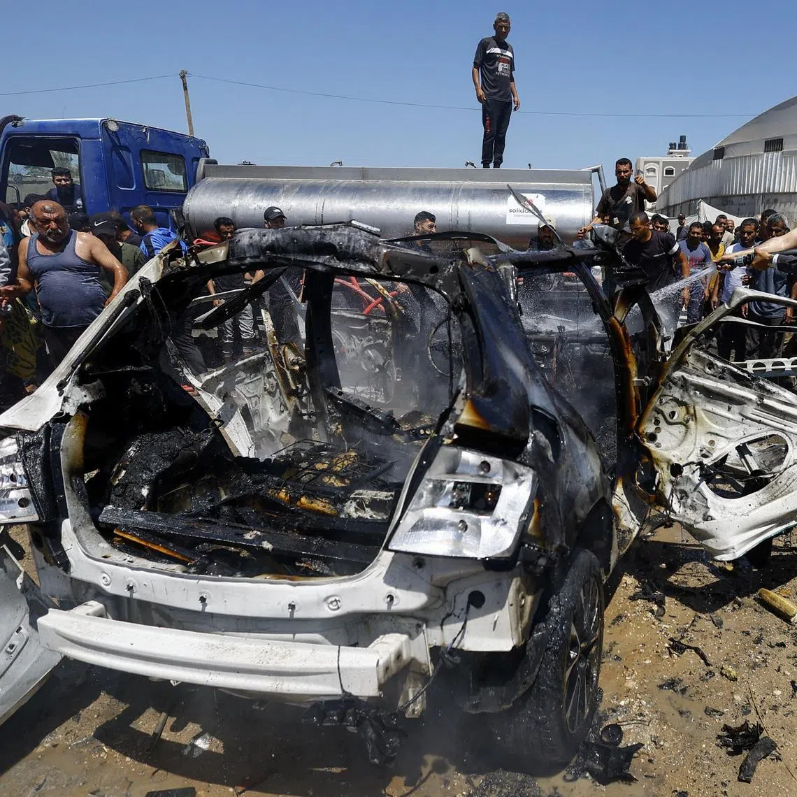 Palestinians gather at the site of an Israeli strike on a vehicle, in Deir al-Balah, in the central Gaza Strip, on June 2.