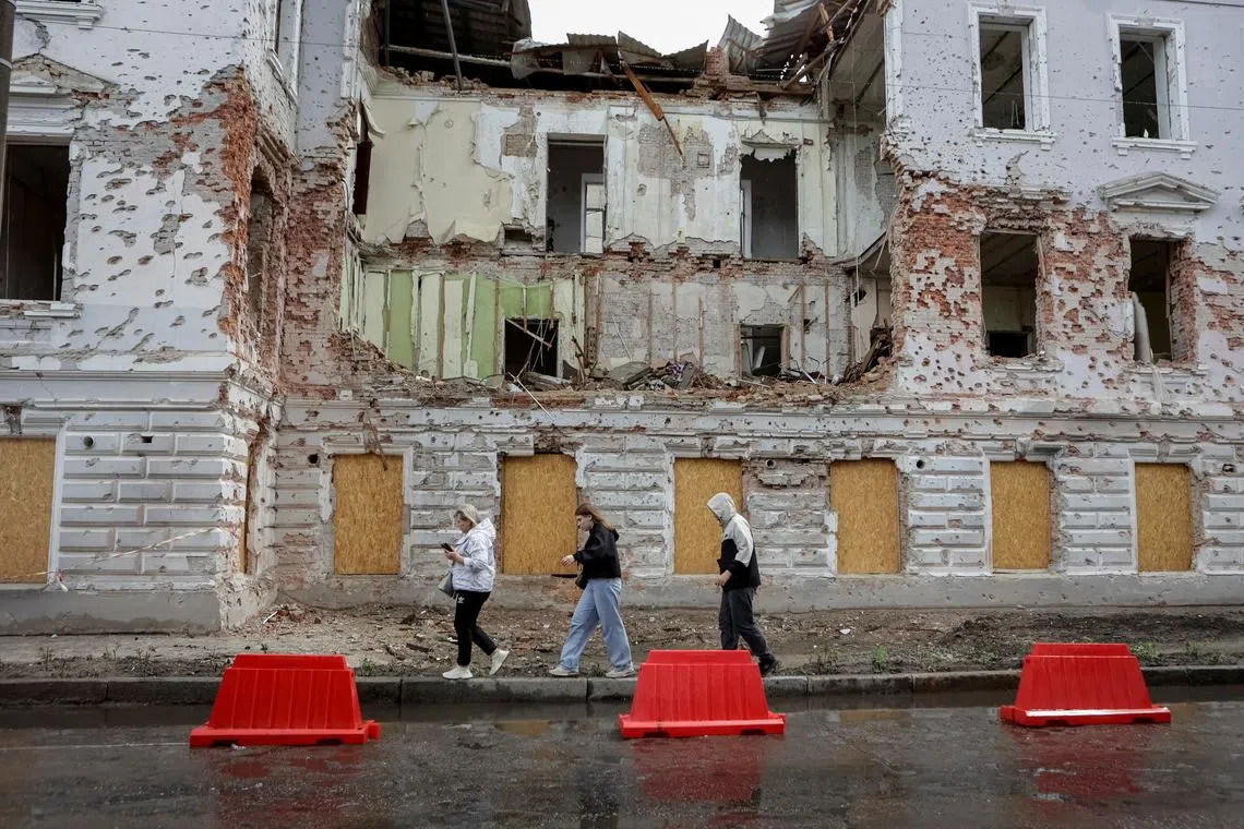FILE PHOTO: Residents walk at a street near a building damaged by Russian missile strikes, amid Russia's attack on Ukraine, in Sumy, Ukraine June 13, 2025. REUTERS/Sofiia Gatilova/File Photo