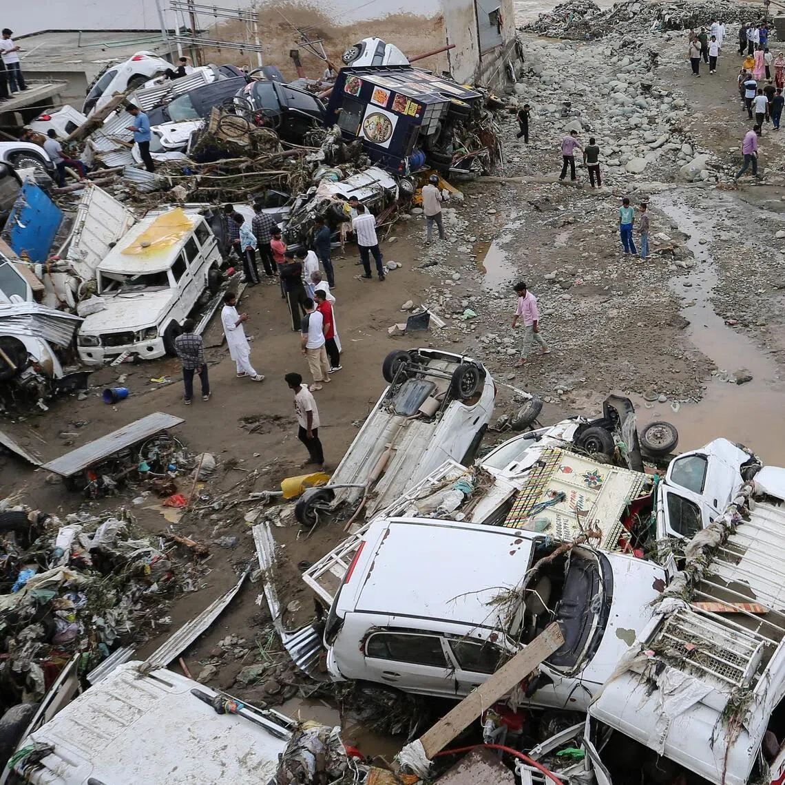 Residents look at damaged vehicles after flash flood and landslide triggered by heavy rains wreaked havoc at Rajouri district in India’s Jammu region on July 19.