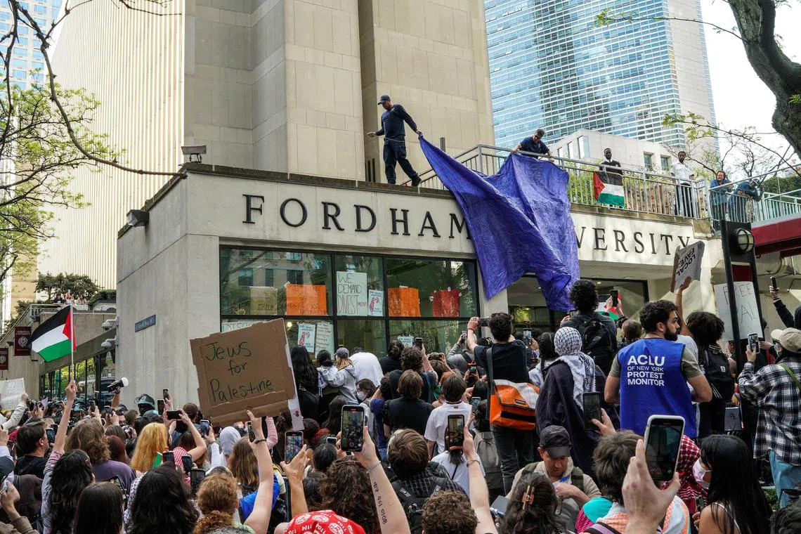 Workers try to cover the Fordham University facade while students and pro-Palestinian protesters rally in front of one of the entrances to the Lincoln Center campus in Manhattan, New York City on May 1. 