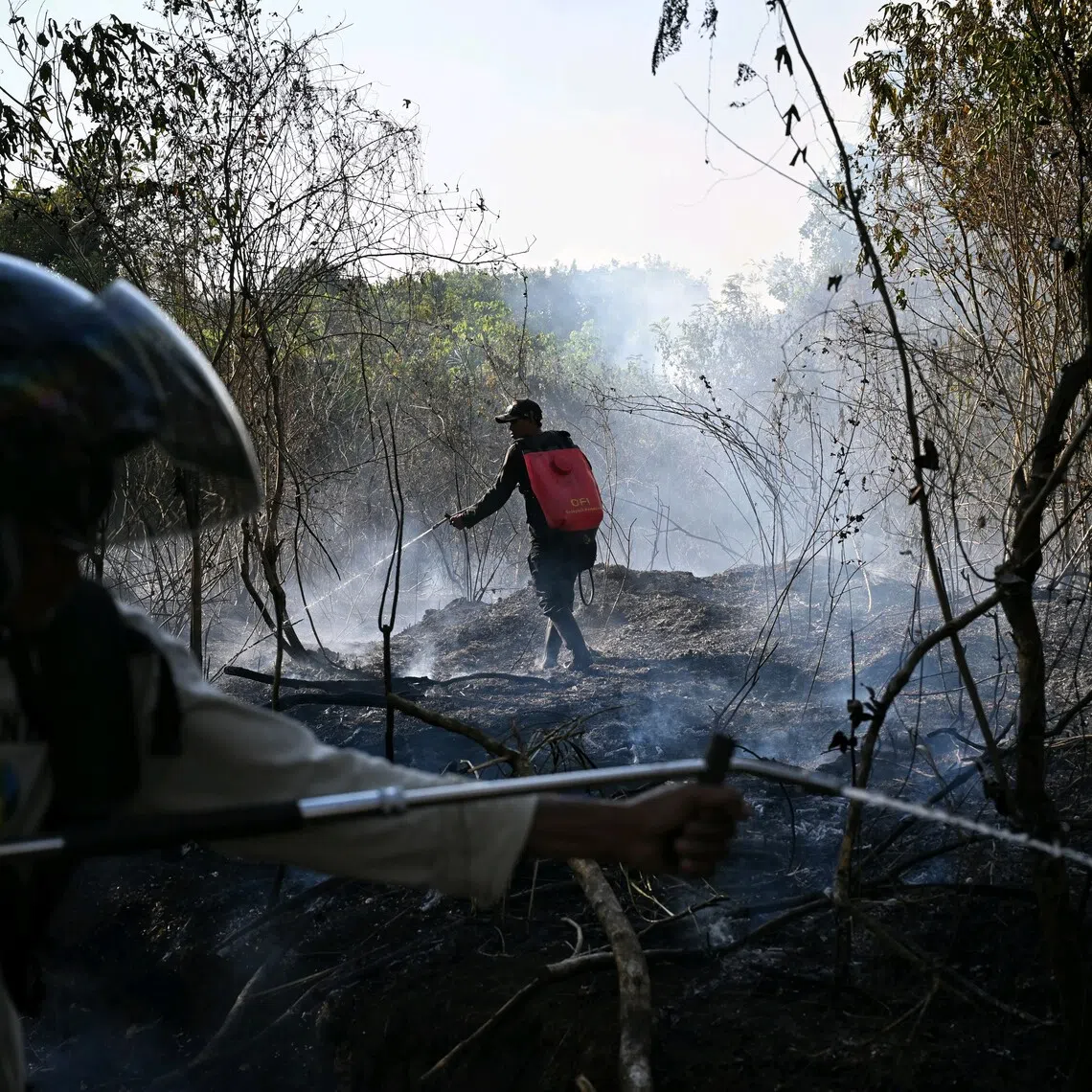 Firefighters putting out a fire in Banjarbaru, in Indonesia’s South Kalimantan province, where ST found that clearing land without fire can still cost considerably more than burning it.