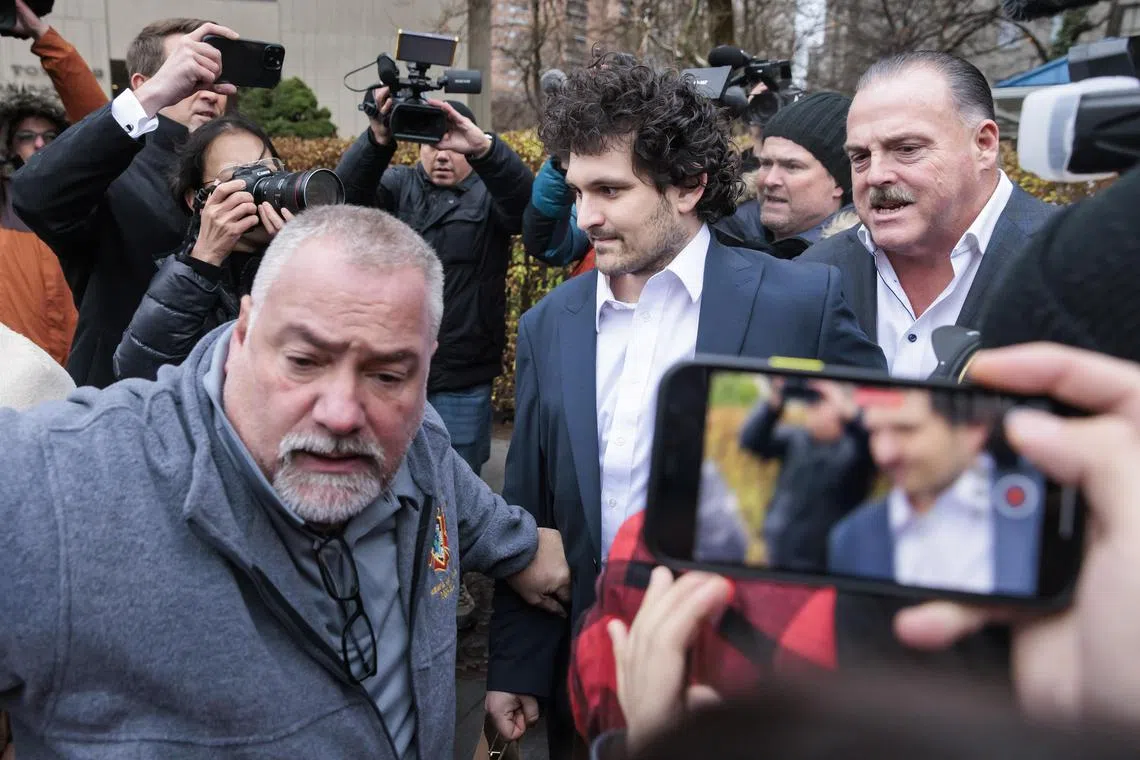 Sam Bankman-Fried (centre) is lead out of court in New York after being released on bail.