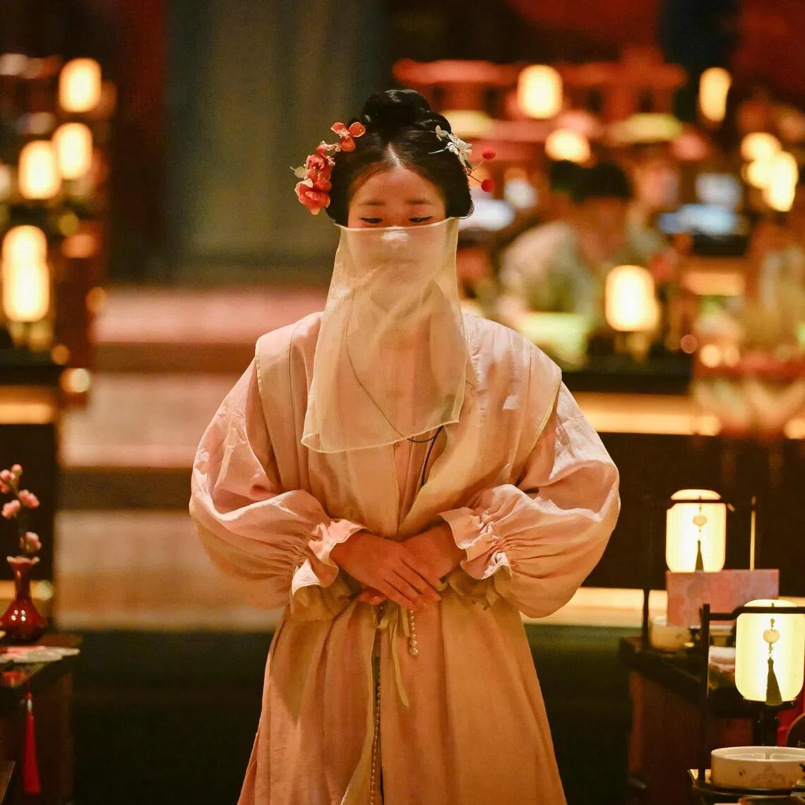 A waitress in traditional Chinese clothes waiting to serve customers at a theatrical restaurant in Beijing.