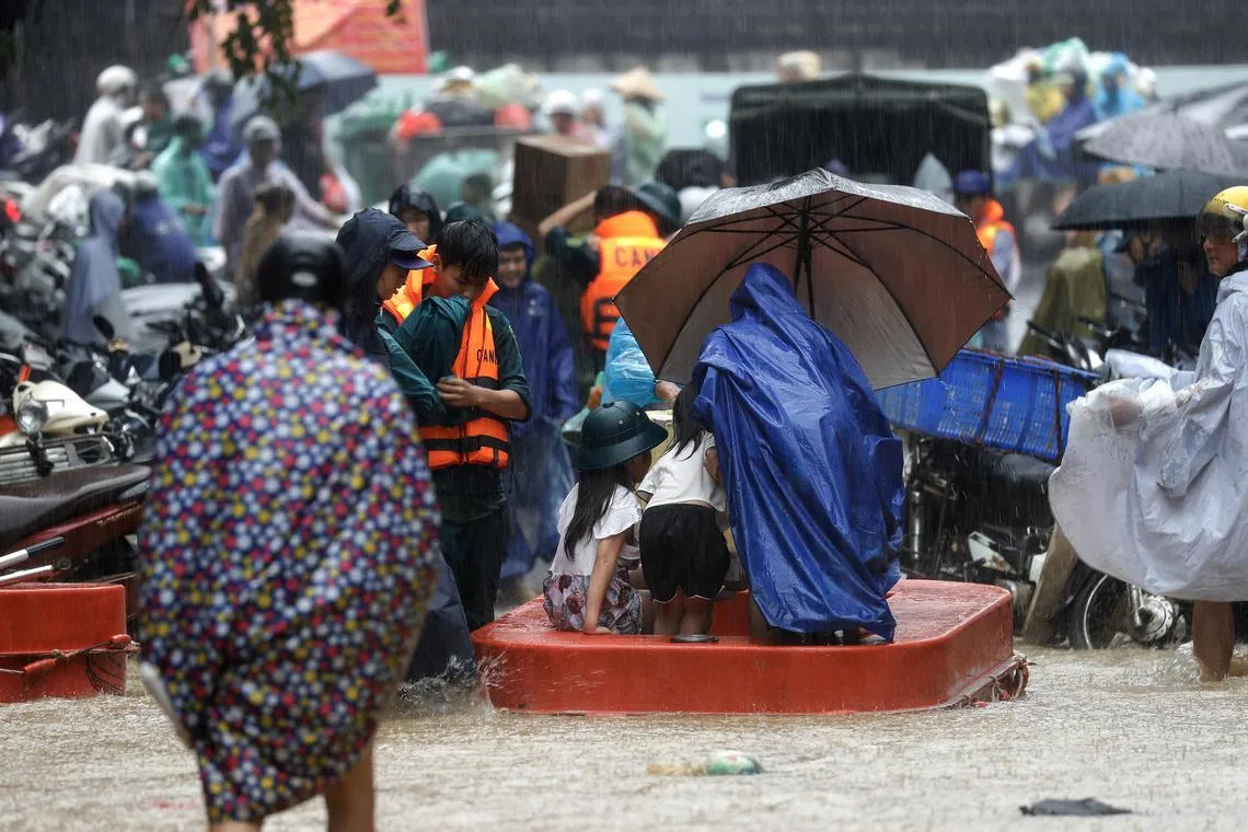 Local residents commute through the flood waters in Hanoi, Vietnam, on Sept 11, 2024.