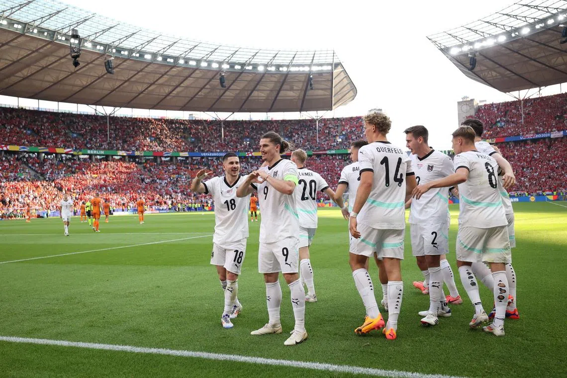 Midfielder Marcel Sabitzer celebrates scoring Austria's third, winning goal with teammates.