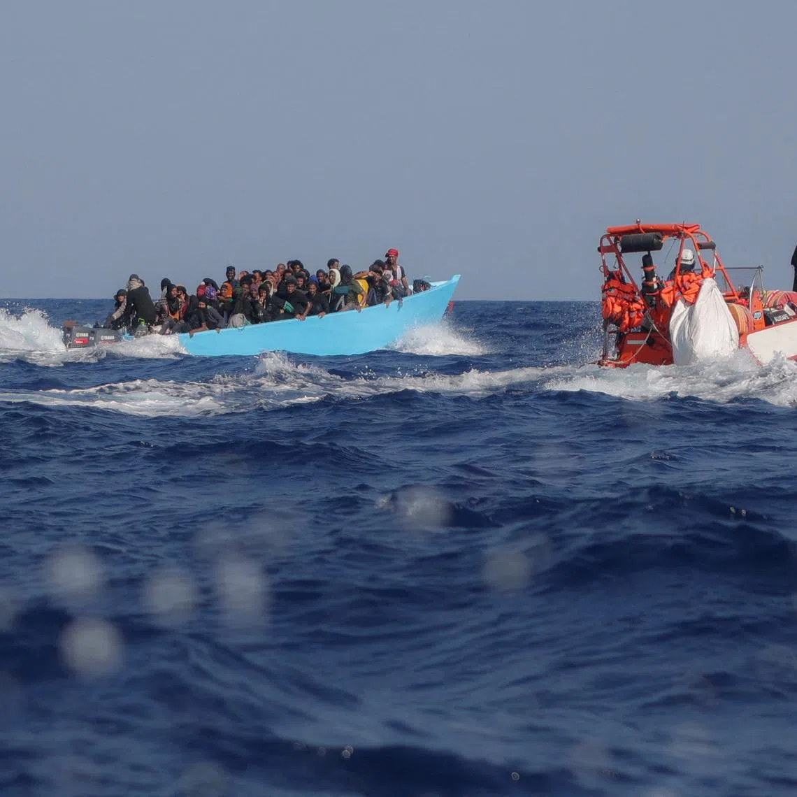 FILE PHOTO: Migrants aboard an overcrowded boat are approached by the crew of the migrant search and rescue ship Sea-Watch 5, operated by the German NGO Sea-Watch, during a rescue operation in the Search and Rescue (SAR) zone in the central Mediterranean, off Libya, August 11, 2025. REUTERS/Louisa Gouliamaki/File Photo