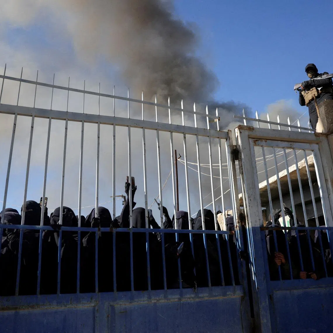 FILE PHOTO: Members of the Syrian government security forces stand guard as a group of female detainees gather at al-Hol camp after the government took control of it following the withdrawal of Syrian Democratic Forces (SDF), in Hasaka, Syria, January 21, 2026. REUTERS/Khalil Ashawi/File Photo