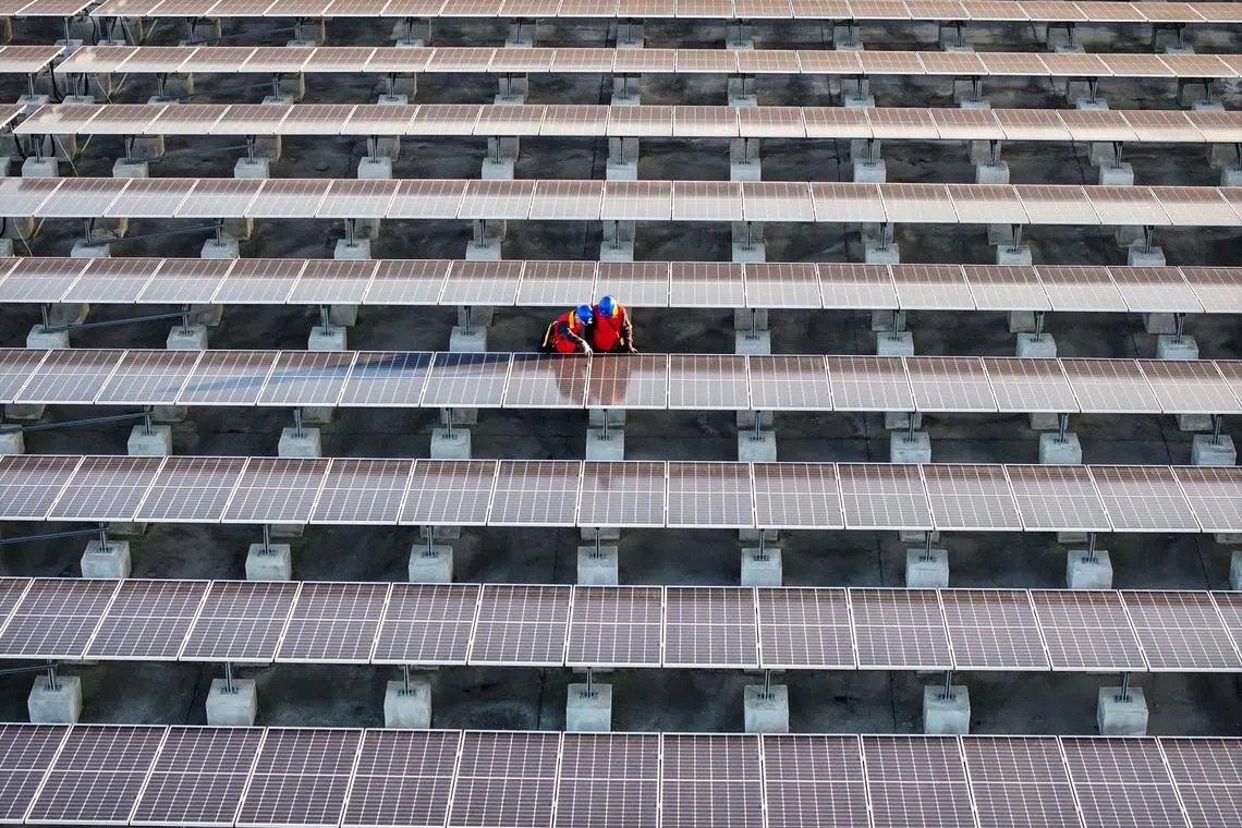 This photo taken on February 21, 2024 shows workers inspecting solar panels at a rooftop of a power plant in Fuzhou, in southern China's Fujian province. (Photo by AFP) / China OUT