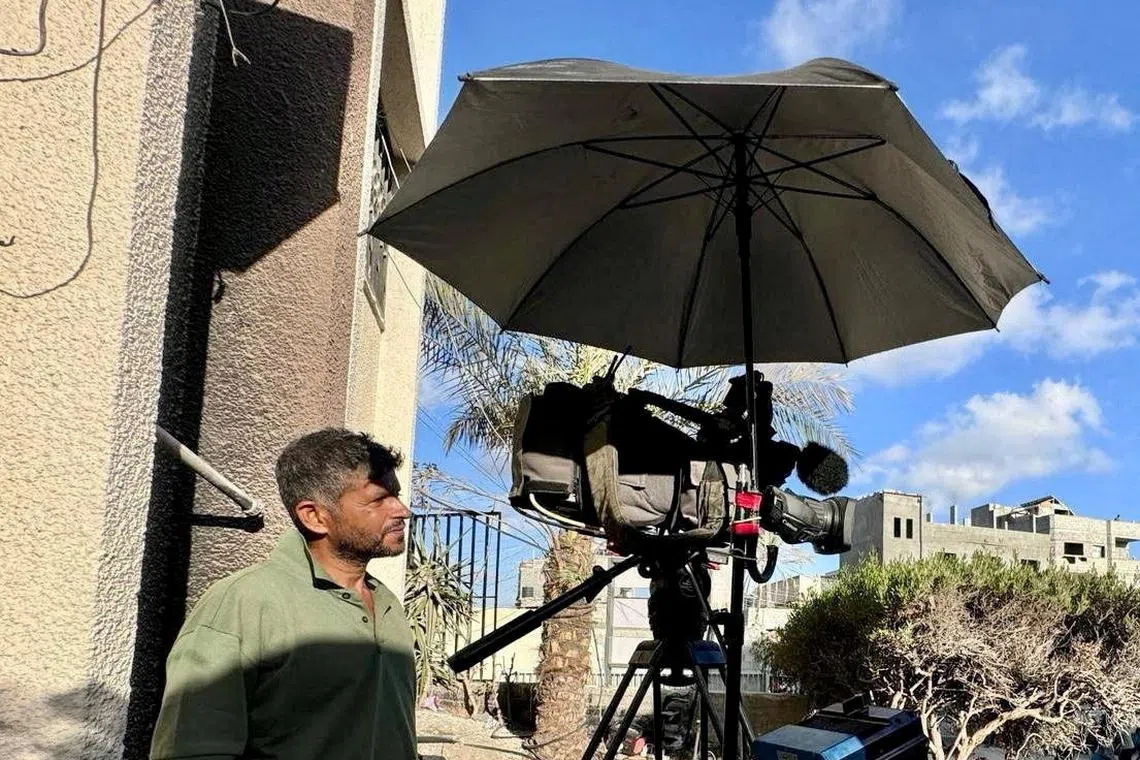 FILE PHOTO: Reuters journalist Hussam al-Masri, who was killed by an Israeli strike on Nasser Hospital on August 25, 2025, stands next to his camera as he works at the hospital in Khan Younis in this undated picture. REUTERS/Mohammed Salem/File Photo