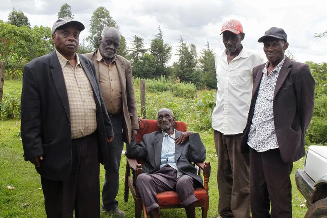 Kibore Cheruiyot Ngasura, 105, a member of the Talai community, which accuses the British colonial government of displacing them from their farms, pose for a picture with his sons outside his house ahead of Britain's King Charles' and Queen Camilla's visit to Kenya, in Tugunon village of Kericho County, Kenya October 25, 2023. REUTERS/Monicah Mwangi