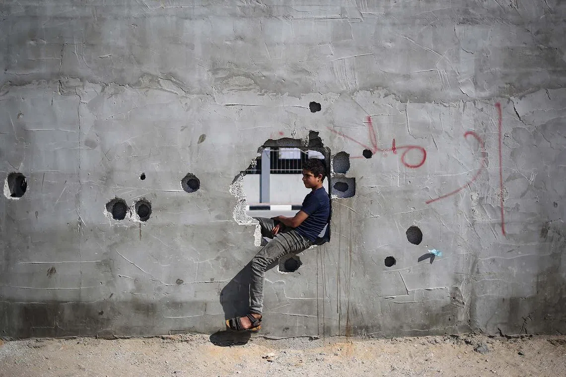 A Palestinian boy sitting and watching aid trucks as they arrive for processing at the Kerem Shalom border crossing on April 15, 2024.