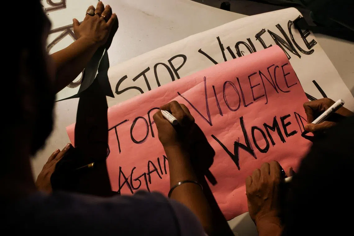 FILE PHOTO: People write slogans on posters before the start of a candlelight vigil condemning the rape and murder of a trainee medic at a government-run hospital in Kolkata, on a street in Mumbai, India, August 14, 2024. REUTERS/Francis Mascarenhas/File Photo