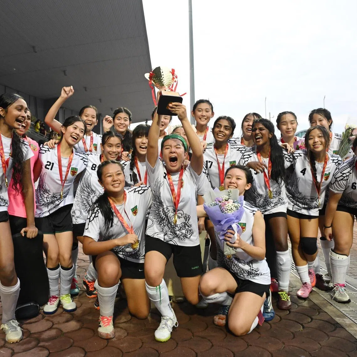 Raffles Institution captain Danica Goh (centre) lifting the trophy after her school's victory over Victoria Junior College in the A Division hockey girls' final. 