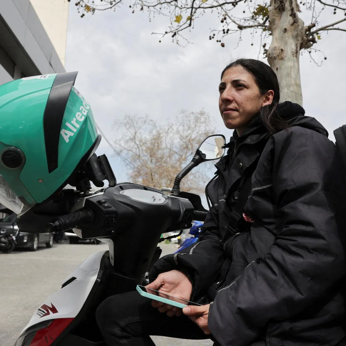 Marie Katanjian, who works as a delivery driver for the Toters delivery app, sits on her scooter in Beirut, Lebanon, March 18, 2026. REUTERS/Emilie Madi