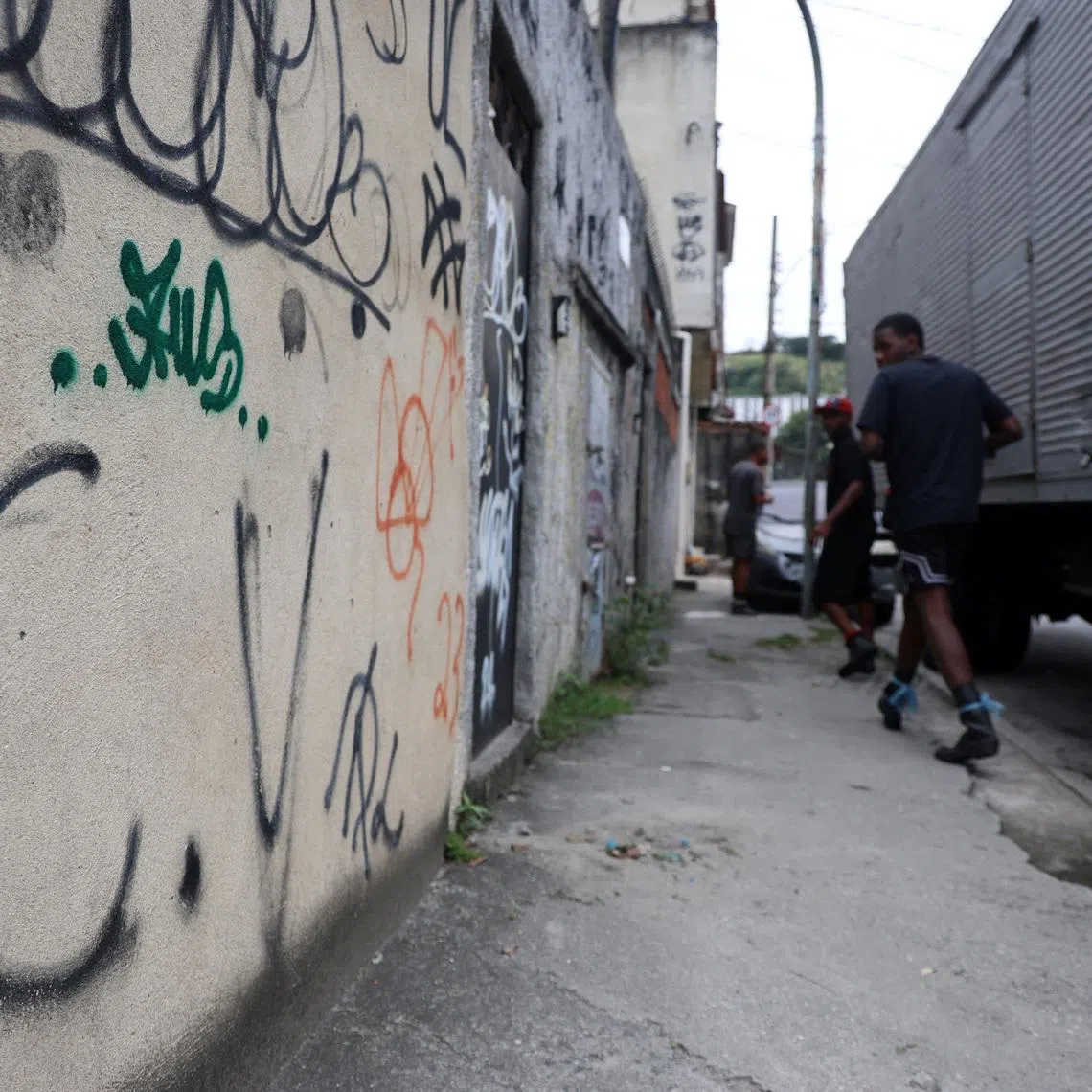 People walk past graffiti reading \"C.V\", referring to a Brazilian gang Comando Vermelho, in Penha neighborhood in Rio de Janeiro, Brazil May 29, 2026. REUTERS/Aline Massuca