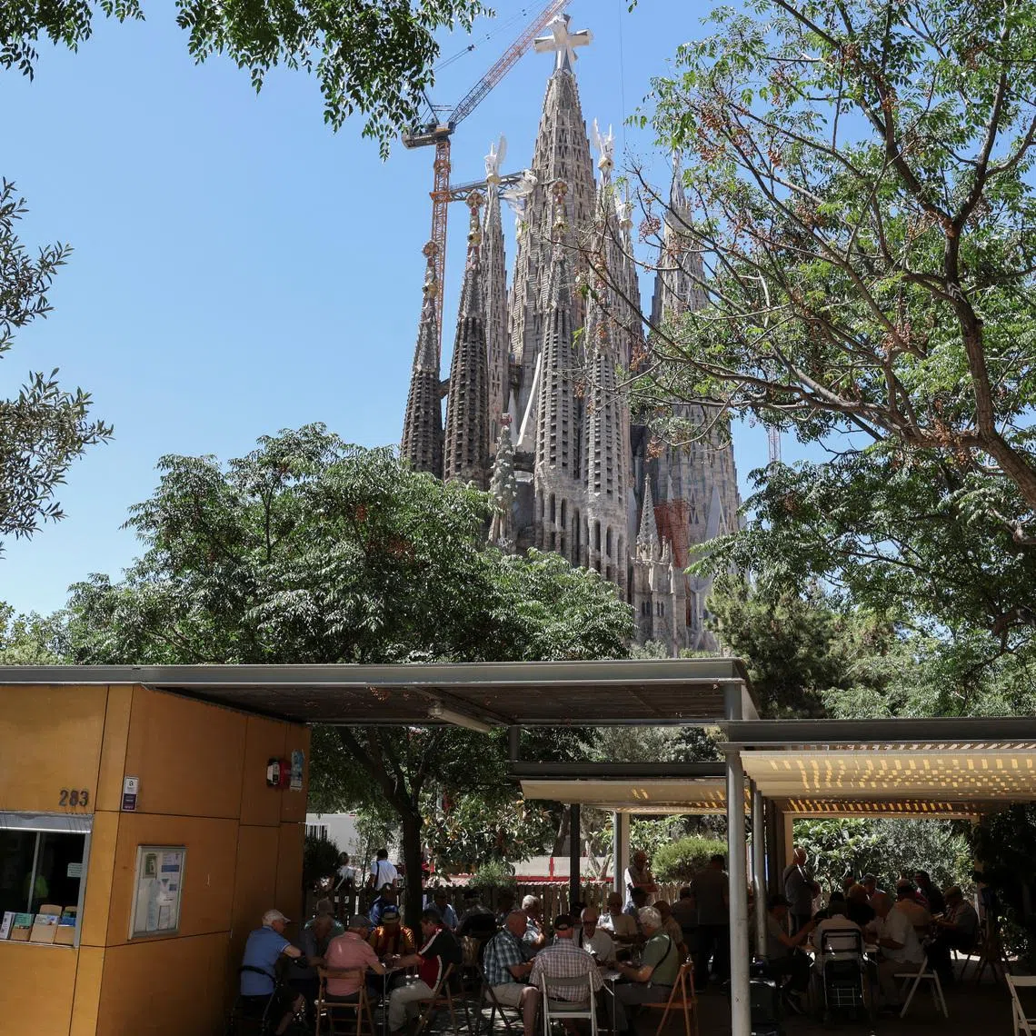 Neighbours play cards and dominoes in front of the Sagrada Familia basilica, designed by Catalan architect Antoni Gaudi, ahead of Pope Leo XIV's visit to Barcelona, ​​Spain, June 3, 2026. REUTERS/Nacho Doce