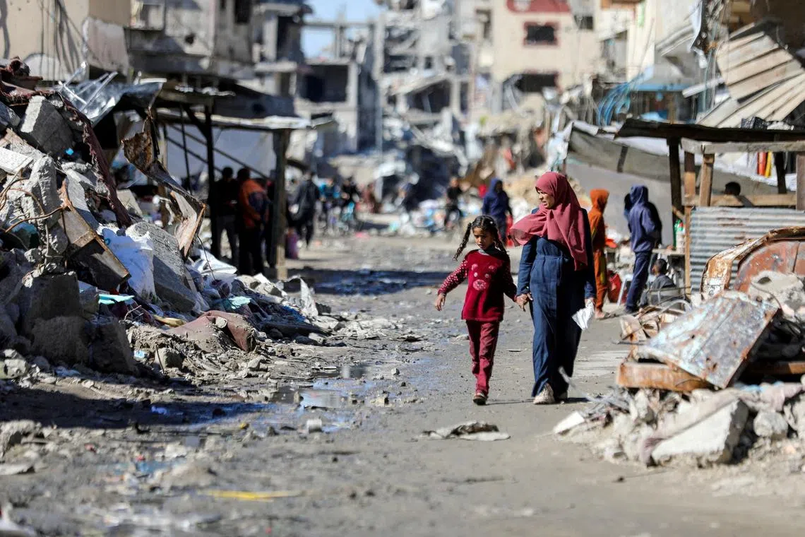 FILE PHOTO: Palestinians walk past the ruins of houses destroyed during Israel's military offensive, amid the ongoing conflict between Israel and Hamas, in Gaza City, March 20, 2024. REUTERS/Dawoud Abu Alkas//File Photo