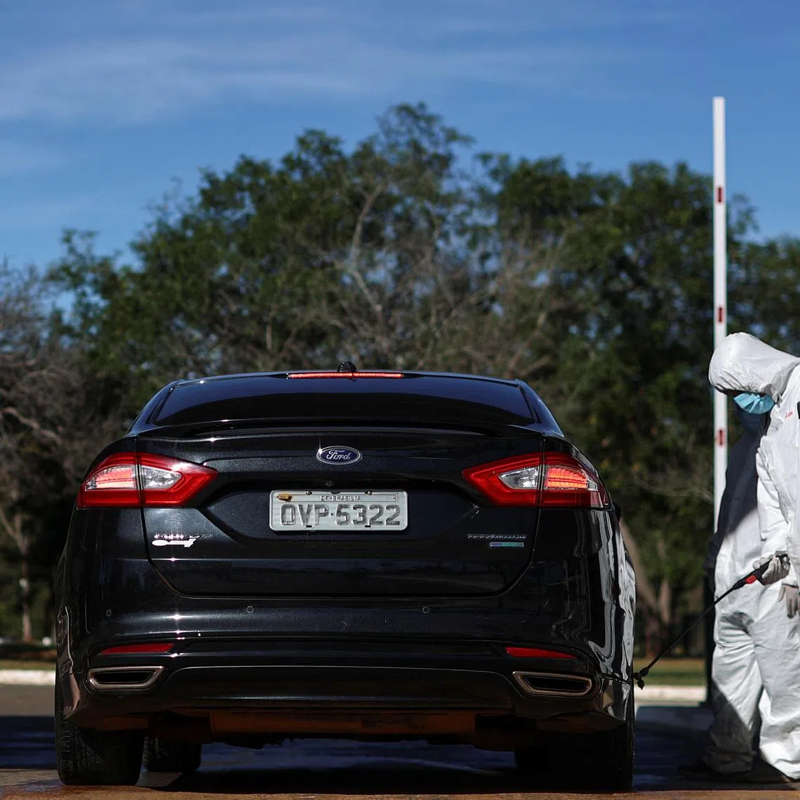 A person wearing a hazmat suit disinfects a car at the entrance to the park, after a confirmed outbreak of bird flu found in two birds in the Zoo, in Brasilia, Brazil June 4, 2025. REUTERS/Adriano Machado