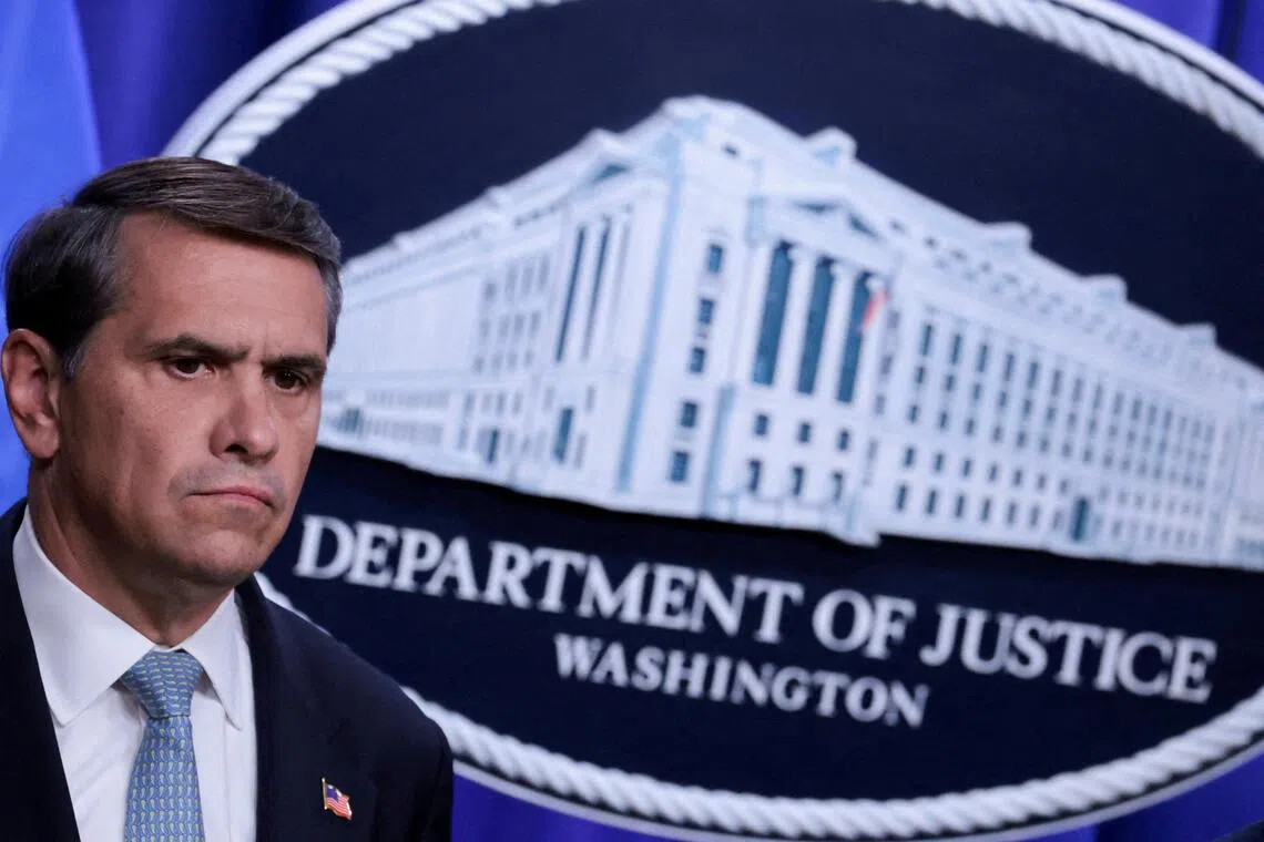A man in a suit stands next to a graphic of the Department of Justice building.
