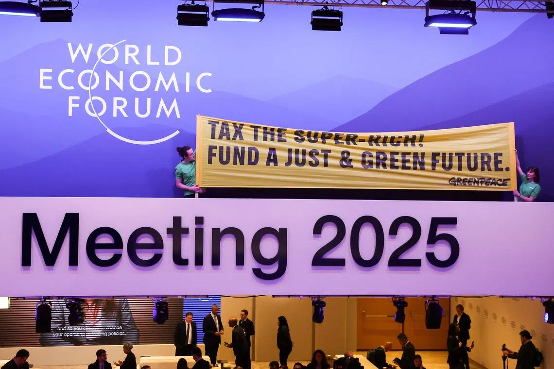 Greenpeace activists hold a banner as they protest in the Congress Centre during the 55th annual World Economic Forum (WEF) meeting in Davos, Switzerland, January 21, 2025. REUTERS/Yves Herman