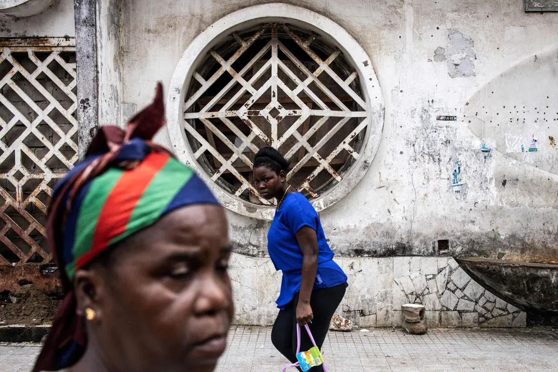 Woman walking past the front of an old derelict building in Monrovia on Oct 11.