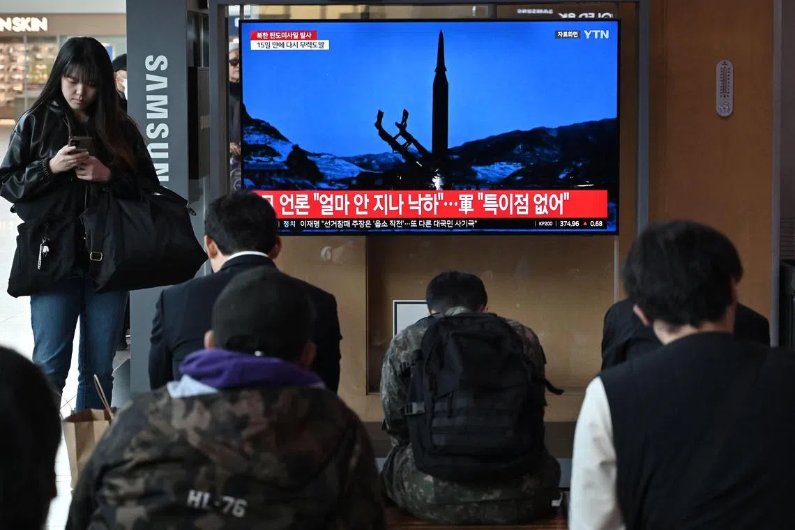People watch a television screen showing a news broadcast with file footage of a North Korean missile test, at a railway station in Seoul on April 2.