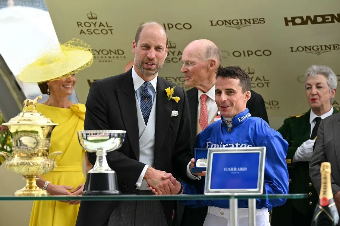 Britain's Prince William, Prince of Wales alongside his wife, Princess Catherine, Princess of Wales, presenting jockey William Buick, with trainer John Gosden standing behind, with his award for riding Ombudsman to win the Group 1 Prince Of Wales's Stakes (2,000m) on the second day of the Royal Ascot meeting in Ascot.