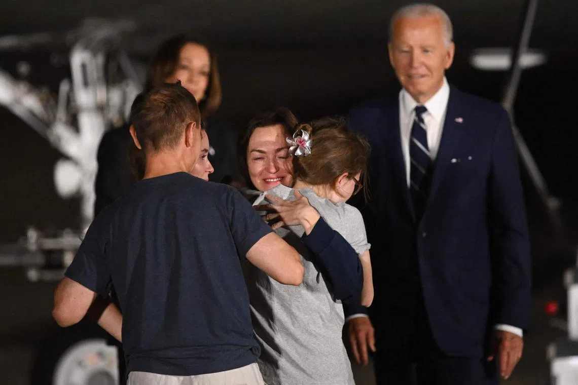 US President Joe Biden and Vice President Kamala Harris watch as former prisoner held by Russia US-Russian journalist Alsu Kurmasheva embraces her family as she arrives at Joint Base Andrews in Maryland on August 1, 2024. Biden hailed the prisoner swap with Russia as a "feat of diplomacy" that has ended their "agony." Jailed US journalist Evan Gershkovich and a Russian intelligence colonel jailed for a Berlin murder were among two dozen prisoners freed August 1, 2024 in the biggest East-West prisoner swap since the Cold War. In total, 10 Russians -- including two minors -- were exchanged for 16 Westerners and Russians imprisoned in Russia, said a statement released by the Turkish presidency. (Photo by ROBERTO SCHMIDT / AFP)