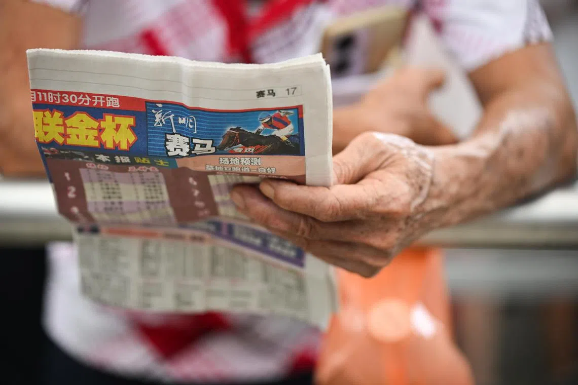 A punter reads a newspaper about the races, examining the odds and statistics before placing a bet.