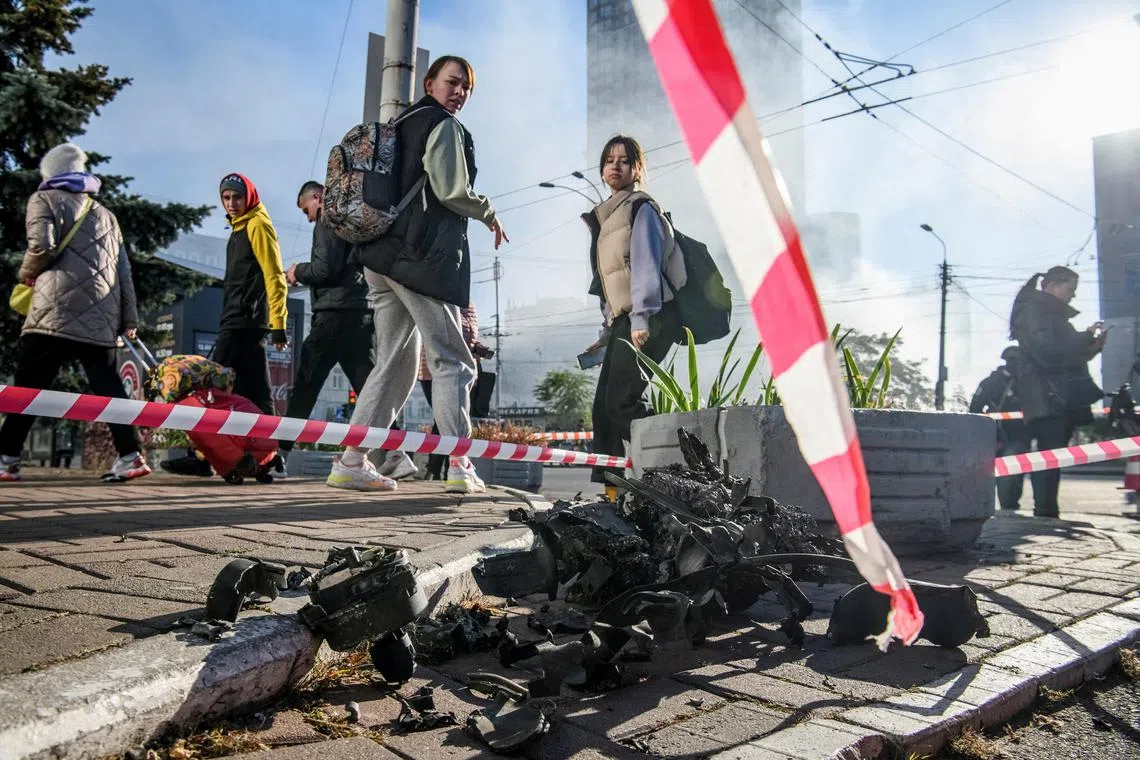 Local residents looking at the remains of what is said to be an Iranian-made drone, following a drone strike in Kyiv, Ukraine, on Oct 17, 2022.