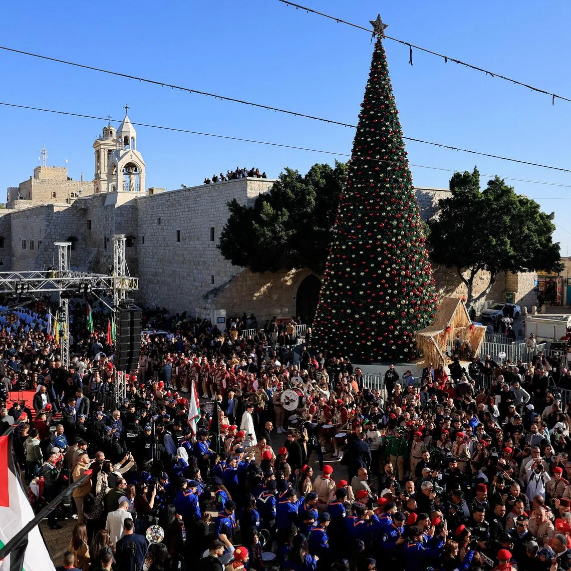 People gather next to the Christmas tree at Manger Square on Christmas Eve, in the Old City of Bethlehem in the Israeli-occupied West Bank.