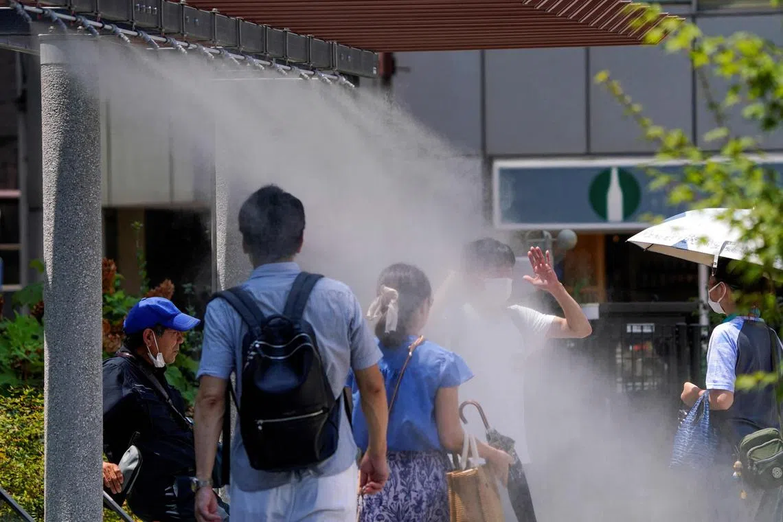 Pedestrians cool off in water mist during heatwave conditions in Tokyo on July 18, 2023
