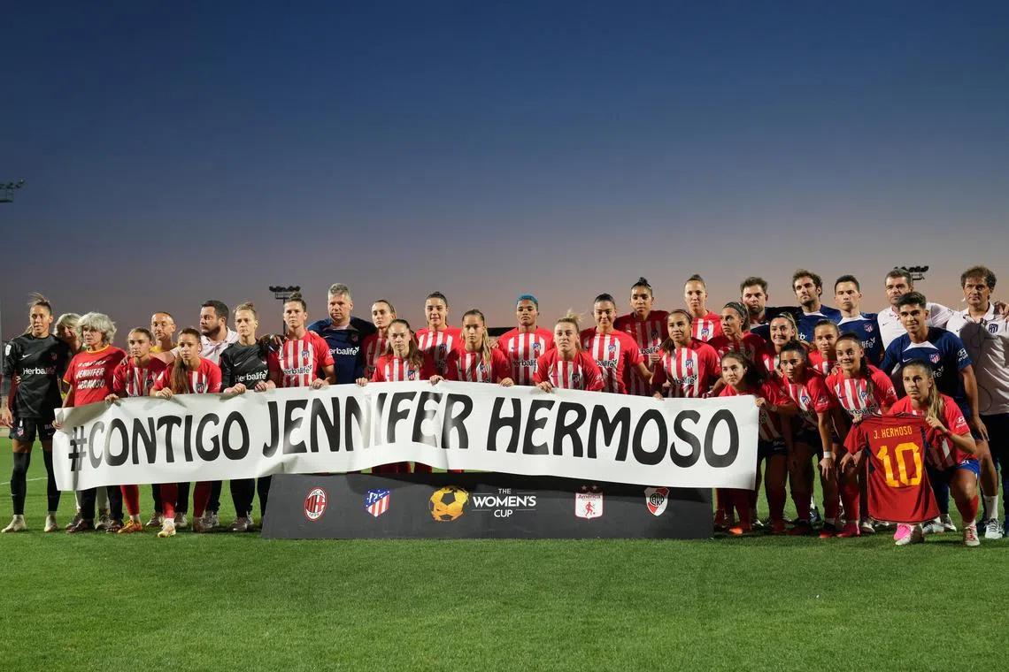 Atletico Madrid players and staff hold a banner which reads "With You Jennifer Hermoso" in support of the Spanish player before their match.
