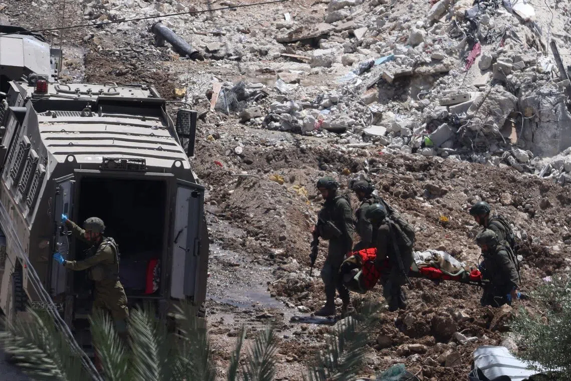 Israeli soldiers removing a body from a demolished home, during a raid in the occupied West Bank town of Deir al-Ghusun, near Tulkarem, on May 4, 2024.