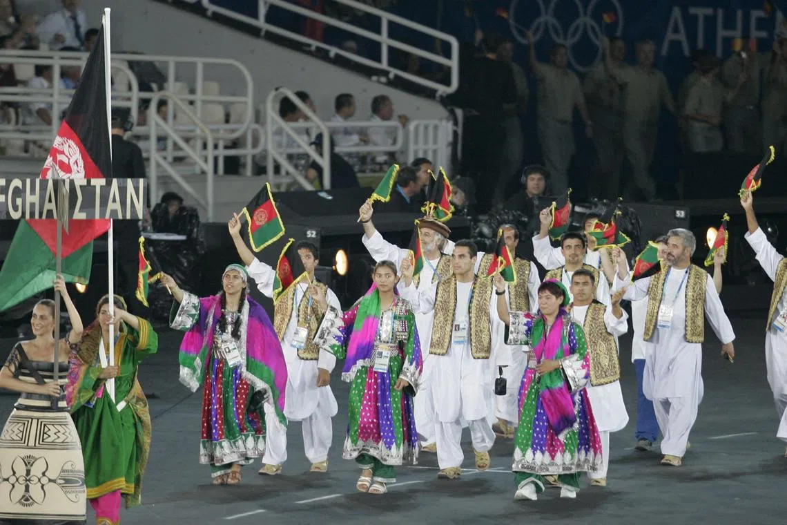 FILE PHOTO: Afghanistan's Nina Suratger holds Afghanistan's national flag during the opening ceremony of the Athens 2004 Olympic Games.  Afghanistan's Nina Suratger (2ndL) holds the Afghanistan national flag in front of members of the national team during the opening ceremony of the Athens 2004 Olympic Games August 13, 2004. REUTERS/Mike Blake/File Photo