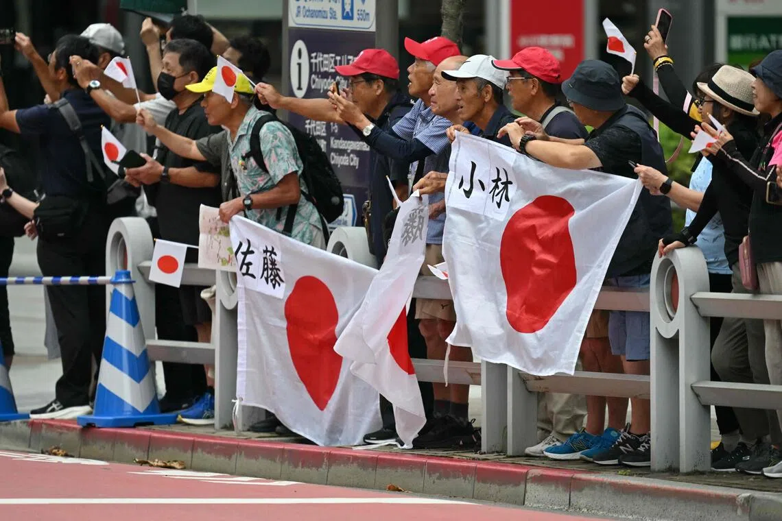 Fans hold the Japan flag to cheer on athletes in the women's marathon final.