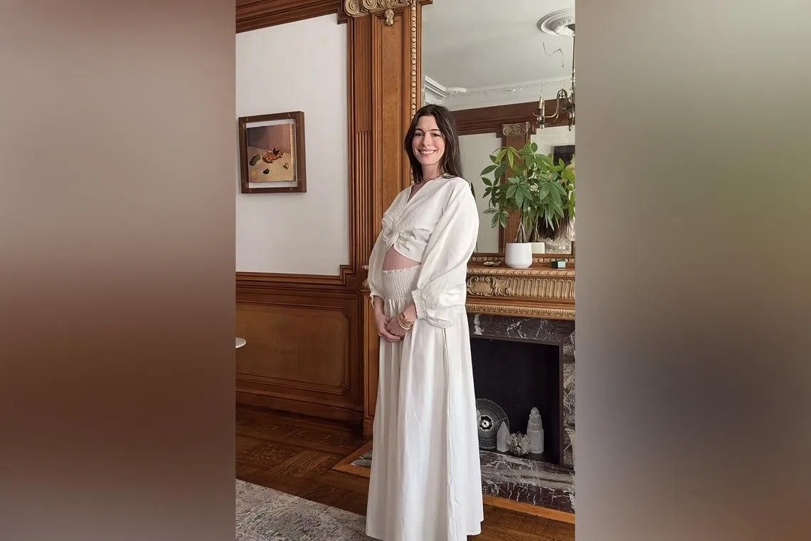Anne Hathaway shared a video on her Instagram account of her stepping into frame and cradling her baby bump in a white flowy outfit as she smiled.
