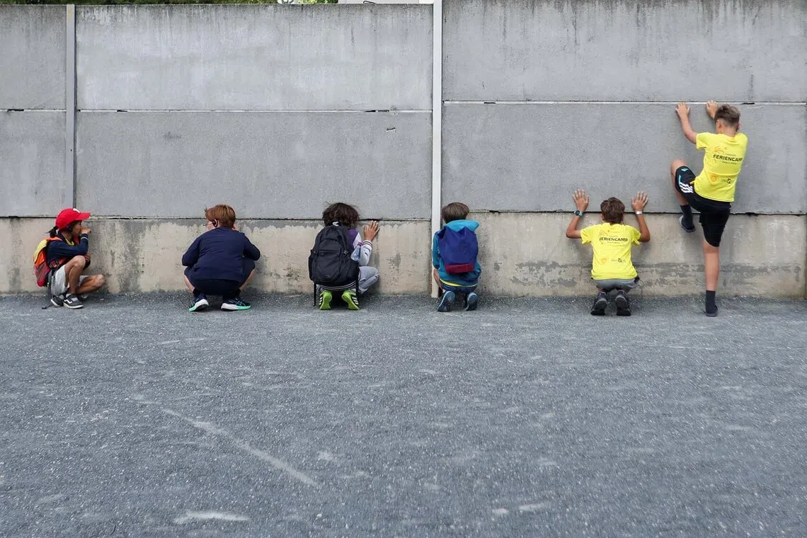 Children examine a preserved section of the Berlin Wall Memorial ahead of the 65th anniversary of the construction of the Berlin Wall, which stretched 155 kilometers (96 miles) and separated East and West Berlin from August 13, 1961, to November 9, 1989, in Berlin, Germany, August 11, 2026. REUTERS/Maryam Majd TPX IMAGES OF THE DAY