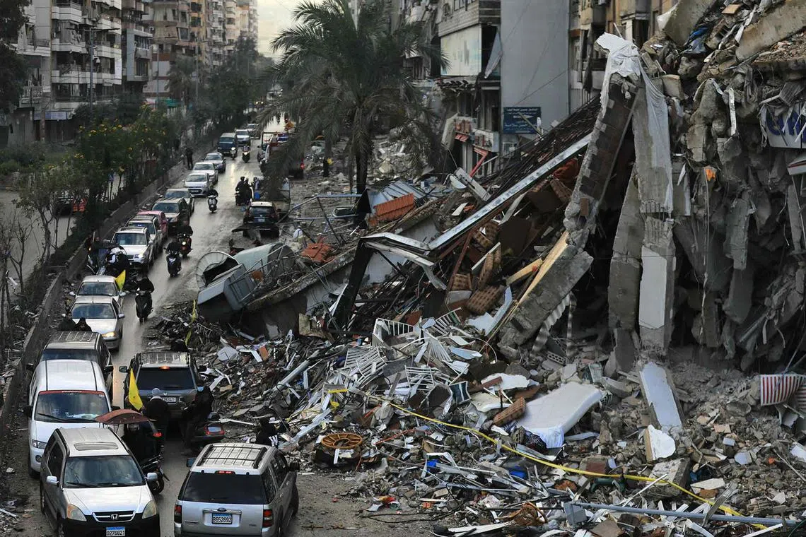 Motorists driving past a destroyed building in Beirut’s southern suburbs on Nov 27, 2024, after a ceasefire between Israel and Hezbollah took effect. A ceasefire between Israel and Hezbollah in Lebanon took hold after more than a year of fighting that has killed thousands, with displaced people returning home in the south, against warnings from both sides. 