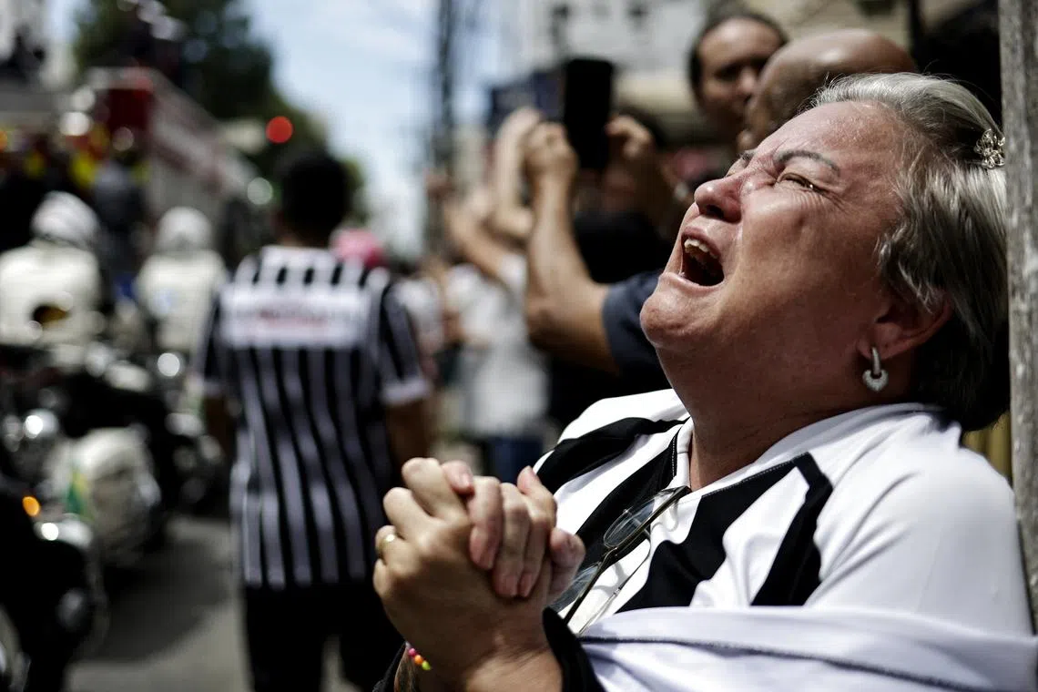 A woman reacts as the casket of Brazilian soccer legend Pele is transported through the streets of Santos, Brazil, Jan 3, 2023. 