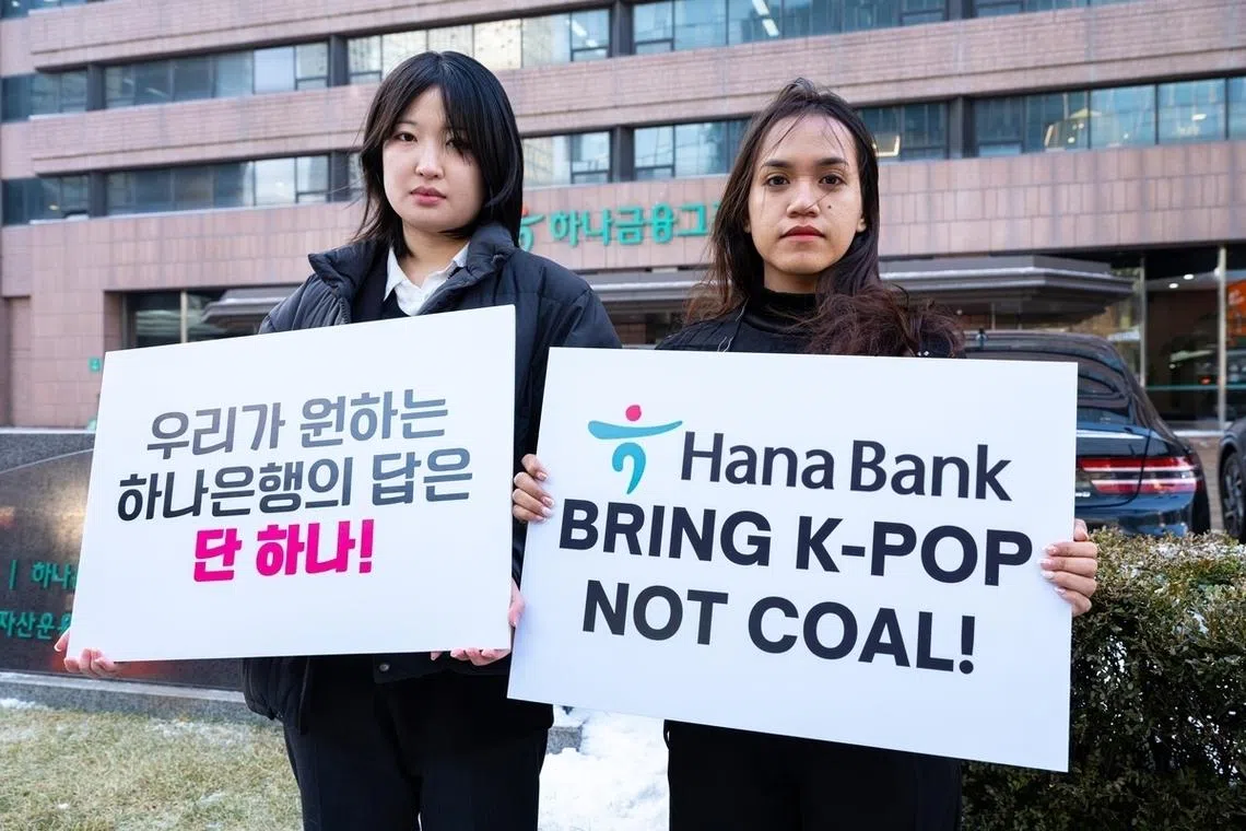 Kpop4planet's Lee Da-yeon (left) and Nurul Sarifah hold signs demanding that Hana Bank cease funding nickel projects on Feb 2.