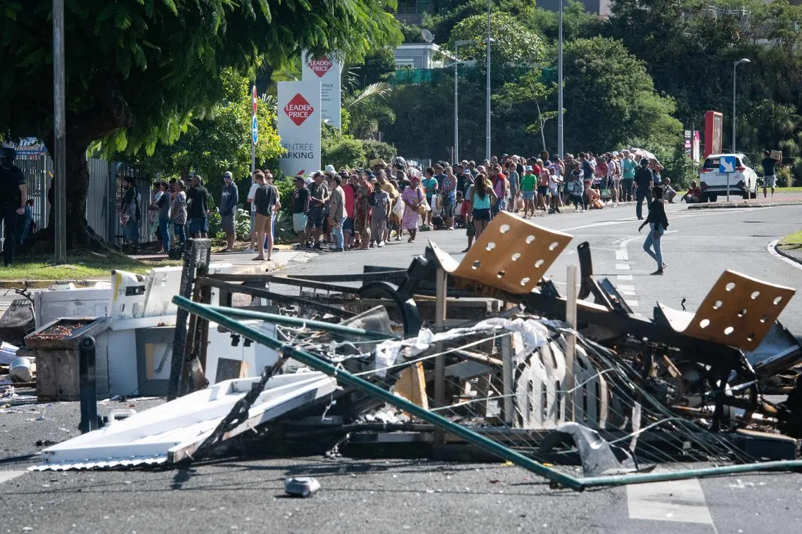 People waiting in line to buy provisions from a supermarket following overnight unrest in the Magenta district of Noumea, in New Caledonia.