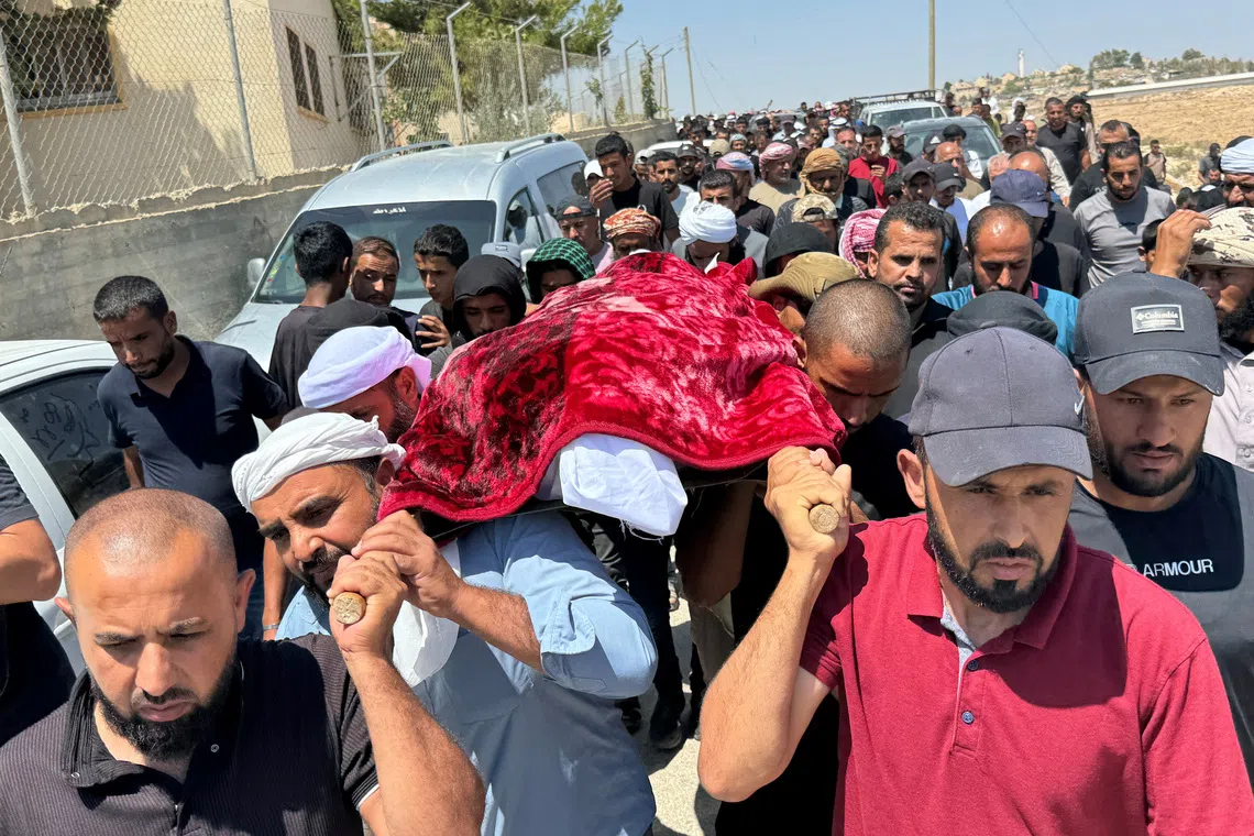 Mourners carry the body of well-known Palestinian activist Owdeh Hathaleen during his funeral near the city of Hebron in the Israeli-occupied West Bank on Aug 7, 2025.